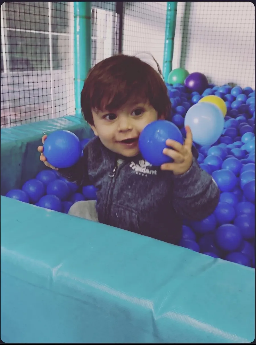 Niño jugando en alberca de pelotas de juegos infantiles